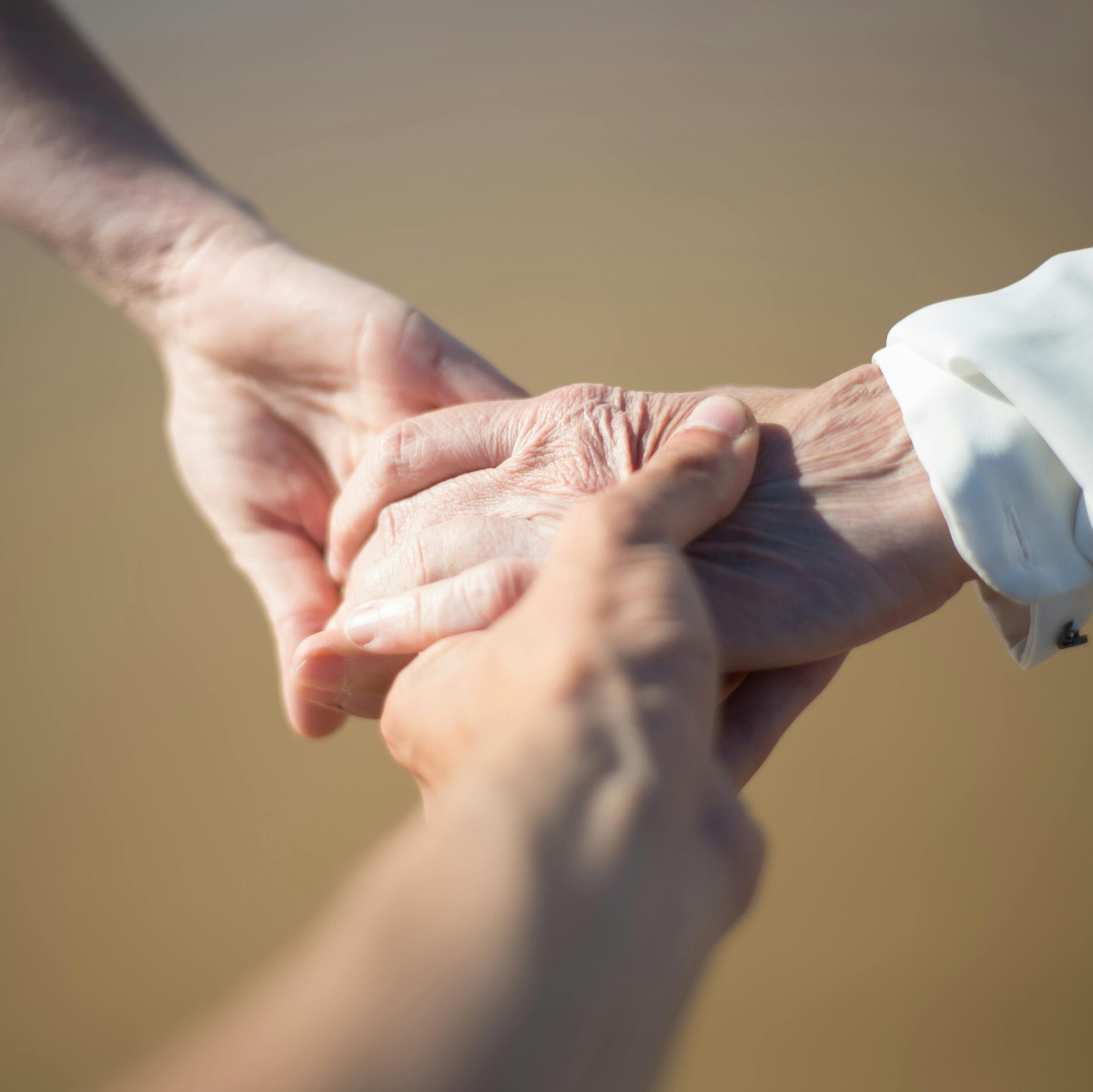 Gentle close-up of intergenerational hands holding, symbolizing connection and care.